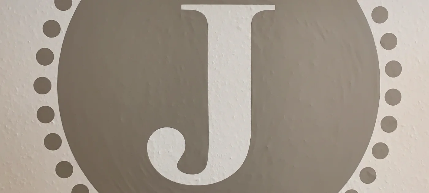 Das Praxiszeichen mit dem Buchstaben J an der Wand