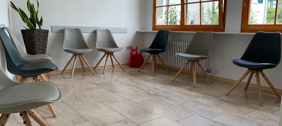 Unser heller Wartebereich mit Sitzgelegenheiten und einem roten Spieltier für Kinder